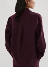 Camisa de lino color bordó con cuello camisero, manga larga con puños abotonados, bolsillo aplicado en el pecho y cierre frontal de botones.