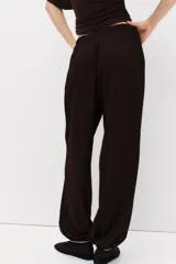 Pantalón globo de corte holgado en punto con textura, color marrón oscuro, con cintura elástica y bajos elásticos.