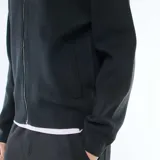 Cardigan de punto color negro con cuello alto y cierre frontal completo. Presenta puños y ruedo acanalados.