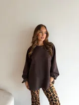 Buzo de punto color marrón chocolate, con cuello redondo, mangas largas con puños elásticos y diseño holgado de largo extendido.
