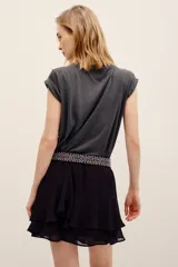 Falda corta color negro con diseño de volados en capas, confeccionada en viscosa con forro de poliéster.