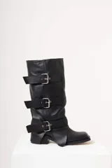 Botas de caña alta confeccionadas en cuero negro, con diseño de estilo motero que presenta tres correas horizontales ajustables con hebillas metálicas plateadas. Poseen puntera cuadrada y taco bajo cuadrado.
