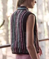 Chaleco tejido a mano en crochet de lana merino color negro, con diseño sin mangas, cuello mao y cierre delantero con cordones para atar. Presenta un patrón de rayas verticales con detalles geométricos en tonos fucsia, celeste y blanco.