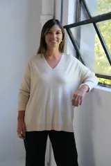 Sweater de punto color crudo, con escote en V, manga larga y diseño holgado con costura central vertical.