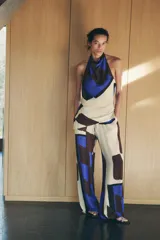 Top de cuello halter con hombros descubiertos, espalda descubierta, detalle de drapeado lateral y bajo asimétrico.