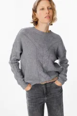 Sweater de punto negro con diseño de trenzas verticales en el frente y cuello redondo. Presenta un corte holgado con puños y ruedo acanalados.