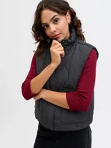 Chaleco acolchado color negro con diseño matelaseado de ondas, cuello alto, cierre frontal con cremallera y bolsillos frontales aplicados.