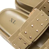 Sandalia mule verde con plataforma texturizada tipo crepe, dos tiras superiores con hebillas cuadradas y tachas metálicas decorativas.