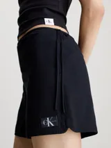 Shorts negros de sirsaca de algodón Calvin Klein, con cintura con cordón, bolsillos con ranura, bolsillos traseros de ojal, forro completo e insignia con el logo de Calvin Klein en el bajo.