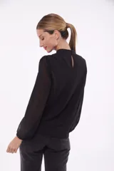 Blusa negra con cuello mao y abertura en forma de gota en el escote. Mangas largas abullonadas de gasa transparente con puños elásticos.