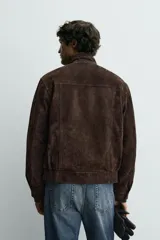 Cazadora regular fit de cuero con acabado serraje en color marrón, cuello subido, bolsillos de plastrón con solapa en la cadera y cierre frontal de cremallera oculta por solapa con botones a presión.