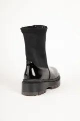 Bota corta negra de símil cuero, con punta redonda, laterales elastizados y suela tipo tractor de 5 cm de alto.