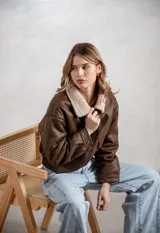 Campera de ecocuero color marrón, con forro interno de corderito sintético, cuello clásico, cierre frontal y bolsillos laterales.