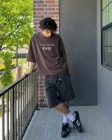 Remera marrón oversize con cuello redondo y mangas cortas. Estampado frontal con el texto "Uruguay Run Club" en celeste y siluetas blancas de personas corriendo.