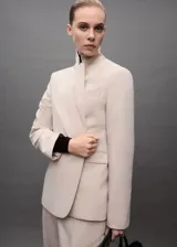 Chaqueta tipo blazer de corte entallado en color beige, con cuello de solapas con muesca, hombros estructurados, cierre frontal de un botón y bolsillos de ribete delanteros.