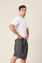 Bermuda deportiva de nylon color negro, de corte suelto, con cintura elástica y cordón de ajuste. Cuenta con detalles de líneas en los costados y bolsillos con cierre.