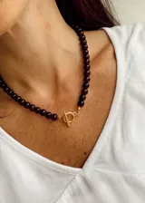 Collar de cuentas esféricas en color marrón oscuro, con cierre frontal tipo marinero en tono dorado.