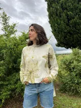 Buzo amplio de frisa liviana de algodón color gris con estampado botánico de hojas en tonos verdes. Tiene cuello redondo y tajos laterales.