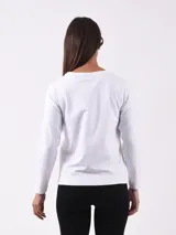 Remera Mahalo de manga larga en color blanco, con cuello redondo y detalle de botones dorados dispuestos en diagonal desde el hombro derecho hasta el pecho.