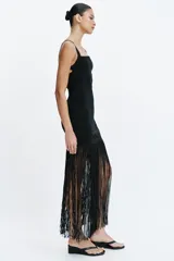 Vestido largo entallado negro con escote cuadrado, tirantes anchos y bajo acabado en flecos largos a tono.