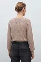 Sweater de punto color beige claro, con escote bote y tejido calado con diseño ondulado. Es de manga larga y corte recto.