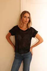 Remera de manga corta con acabado brillante y textura sutil, de corte holgado y cuello redondo. Presenta un diseño versátil y elegante en color negro con destellos dorados.