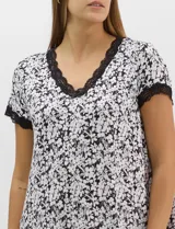 Camisón corto de tejido soft, color blanco con estampado floral y de hojas en tonos azules y marrones. Cuenta con mangas cortas y escote en V con terminaciones de encaje azul en el cuello, las mangas y el ruedo.
