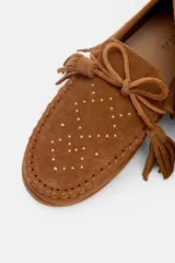 Mocasín de gamuza color bordó con detalle de flecos, cordones y tachas metálicas en la parte superior.