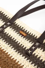 Bolso tipo tote de diseño trenzado con patrón de rayas en tonos marrones y beige, doble asa larga de material sintético oscuro y placa metálica con logo.