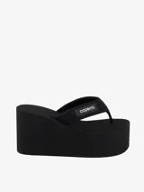 Sandalias de plataforma tipo chancleta de color negro, confeccionadas en neopreno, con suela gruesa de cuña y correas acolchadas con parche de silicona de la marca Coperni.