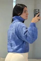 Buzo de chenille color blanco, con cuello alto tipo polera, mangas largas con puños ajustados y diseño de tejido acanalado.