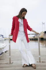 Blazer de lino color rojo, con solapa clásica, bolsillos con solapa en los laterales y cierre frontal de un botón. Las mangas largas presentan detalles de volados en los puños.