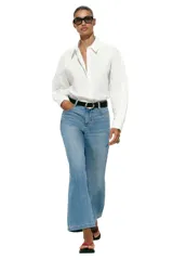 Jeans de tiro alto con pernera ancha y corte cropped. Presenta diseño de cinco bolsillos, cierre frontal con cremallera y botón, e incluye un cinturón oscuro con hebilla metálica.