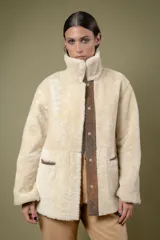 Campera tipo borrego de cuero con efecto desgastado, con interior y cuello de piel sintética en color crema. Presenta cierre frontal con botones a presión y bolsillos frontales amplios.