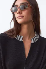 Campera bomber negra de tejido de punto con cuello, puños y ruedo acanalados con rayas blancas.