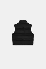 Chaleco acolchado de cuello subido con cierre frontal de cremallera. Presenta bolsillos laterales con cremallera y bajo ajustable con cordones elásticos.