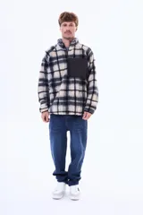 Campera de sherpa con diseño a cuadros en tonos marrón y azul marino. Presenta cuello alto, cierre frontal parcial y un bolsillo frontal con cierre en contraste de color azul marino.