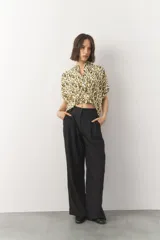 Blusa corta de manga corta con estampado en blanco y negro, cuello mao y cierre frontal con botones. Cuenta con detalle de elástico fruncido en la cintura que genera un efecto peplum.