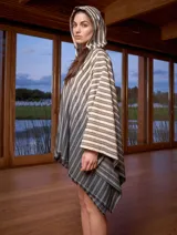 Poncho con capucha a rayas horizontales verdes y blancas, con falda a rayas verticales rosas y marrones.