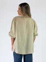 Camisa de lino color celeste, con cuello camisero, cierre frontal con botones y mangas abullonadas tres cuartos.