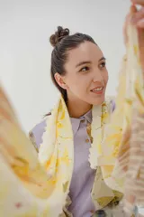 Pañuelo rectangular de tela fina color crema con estampado artesanal de hojas y flores en tonos amarillos y marrones.