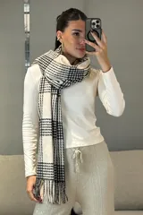 Bufanda rectangular con diseño de cuadros escoceses en blanco y negro, con flecos en los extremos.