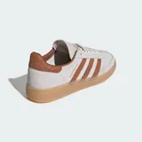 Championes Adidas Handball Spezial de diseño clásico, confeccionados en gamuza color beige con las icónicas tres tiras y refuerzo en el talón con textura de piel de serpiente en tono marrón. Presentan suela de goma color caramelo y detalles dorados en el lateral y la lengüeta.