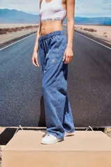 Pantalón de jean azul de corte babucha, tiro medio, con elástico en la cintura, bolsillos delanteros y logo bordado en amarillo en la pierna derecha.