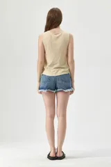 Musculosa color beige con escote en V, sin mangas, con botones y nudo en la parte inferior.