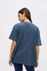 Remera de manga corta color azul, con calce clásico y tajos laterales. Presenta un bordado pequeño en el pecho con el texto 'UNIFORM STUDIO LAB' y un detalle bordado en la manga. Confeccionada en algodón lavado con textura suave.