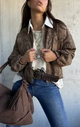 Campera tipo bomber de gamuza color marrón, con diseño bordado de motivos florales en toda la prenda. Presenta cierre frontal, cuello redondo y mangas largas con puños elásticos.