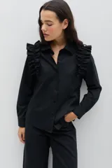 Camisa de gabardina de tencel color negro, con cuello clásico, cierre frontal de botones y volados fruncidos en los hombros.