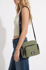 Bandolera color verde militar de nylon, con múltiples bolsillos con cierre en el frente y los laterales, además de una correa ajustable negra.