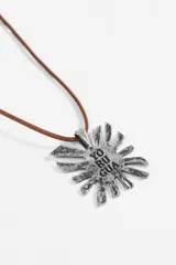 Collar con cordón marrón y dije metálico plateado con forma de sol, que presenta la inscripción 'YO RU GUA' en el centro.